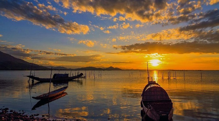 Toàn cảnh phá Tam Giang rộng lớn, với những chiếc thuyền nhỏ và khung cảnh bình minh hoặc hoàng hôn.