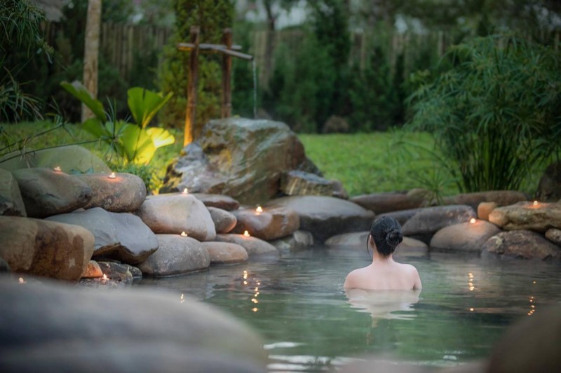 Du khách thư giãn trong bồn onsen với khăn nhỏ trên đầu